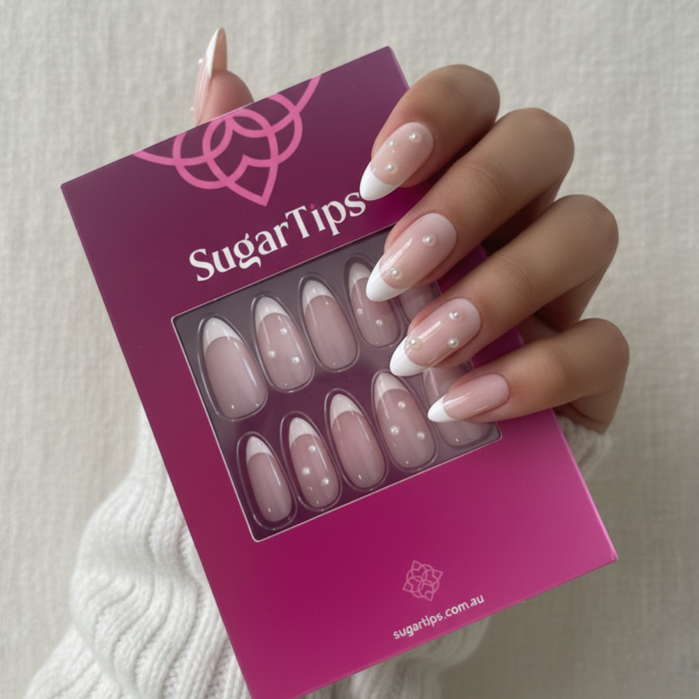 A manicured hand holding a box of Sugar Tips press on nails