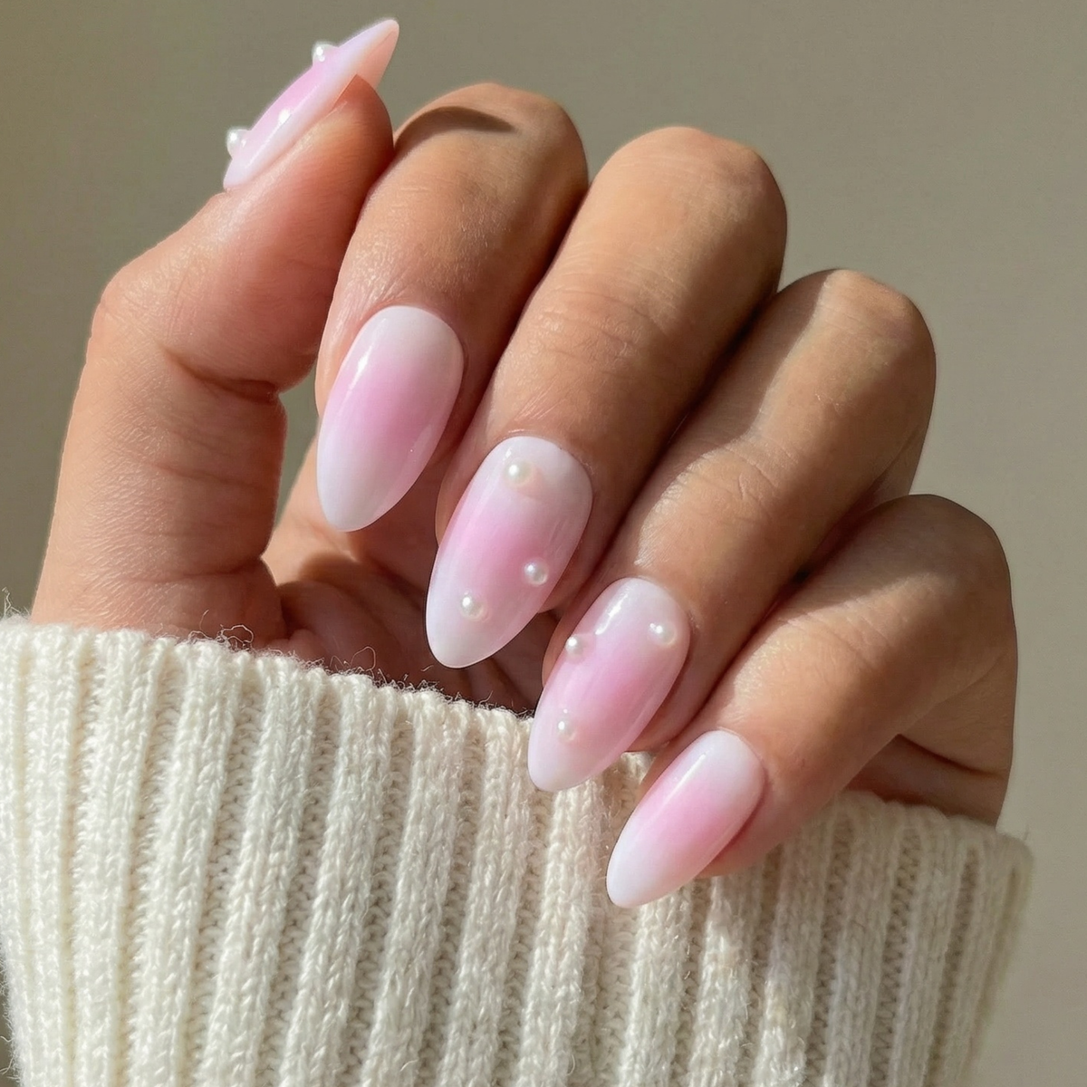 Pastel pink and lavender ombre almond press-on nails by SugarTips, worn with a cream knit sweater