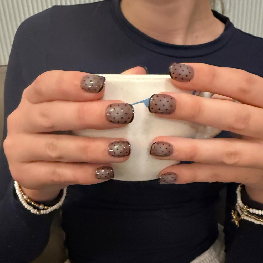Woman holding a coffee mug wearing brown polka dot Sugar Tips press-on nails
