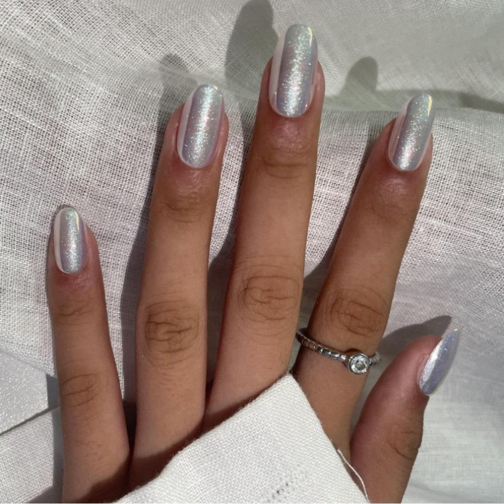 A close-up image of a hand with press-on nails painted in a sparkly chrome color, displaying a simple yet elegant nail art.