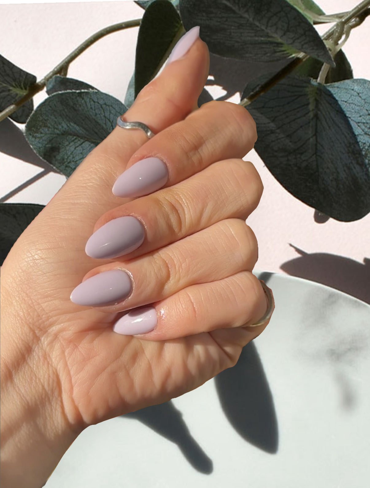 Hand wearing Sugar Tips Lavender Milk Soft Lilac Glossy Almond Press on Nails. against a natural background