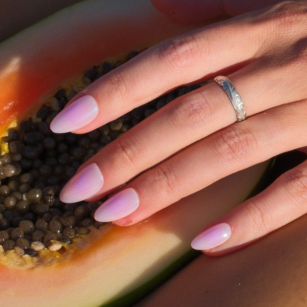 Cotton Candy pink and lavender ombré press-on nails in medium almond by Sugar Tips, resting on a fresh papaya
