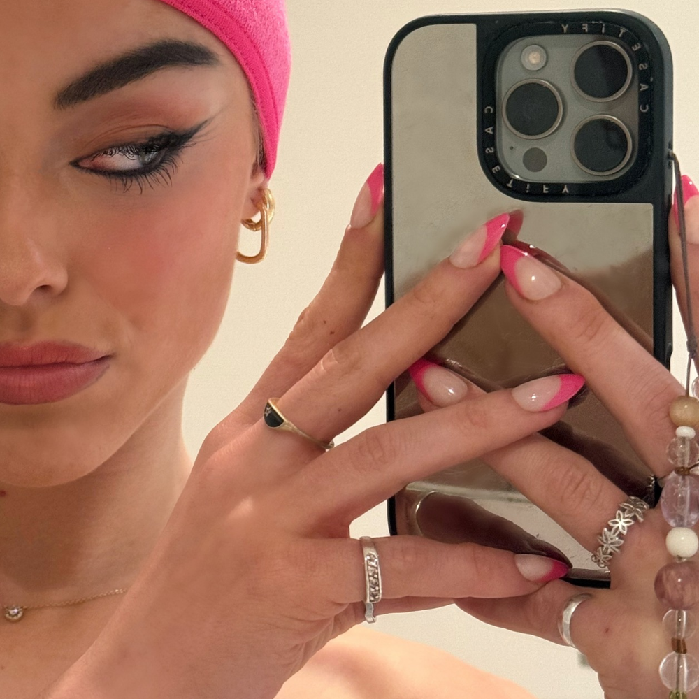 Barbie French hot pink French tip press-on nails in medium almond by Sugar Tips, in a mirror selfie