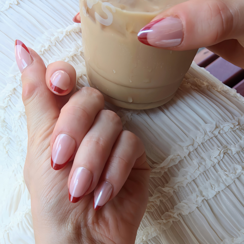 A hand resting on a table showing red tip press on nails from Sugar Tips