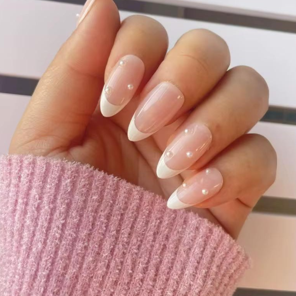 Hand with almond-shaped nails featuring a subtle design, wearing a pink textured sleeve.