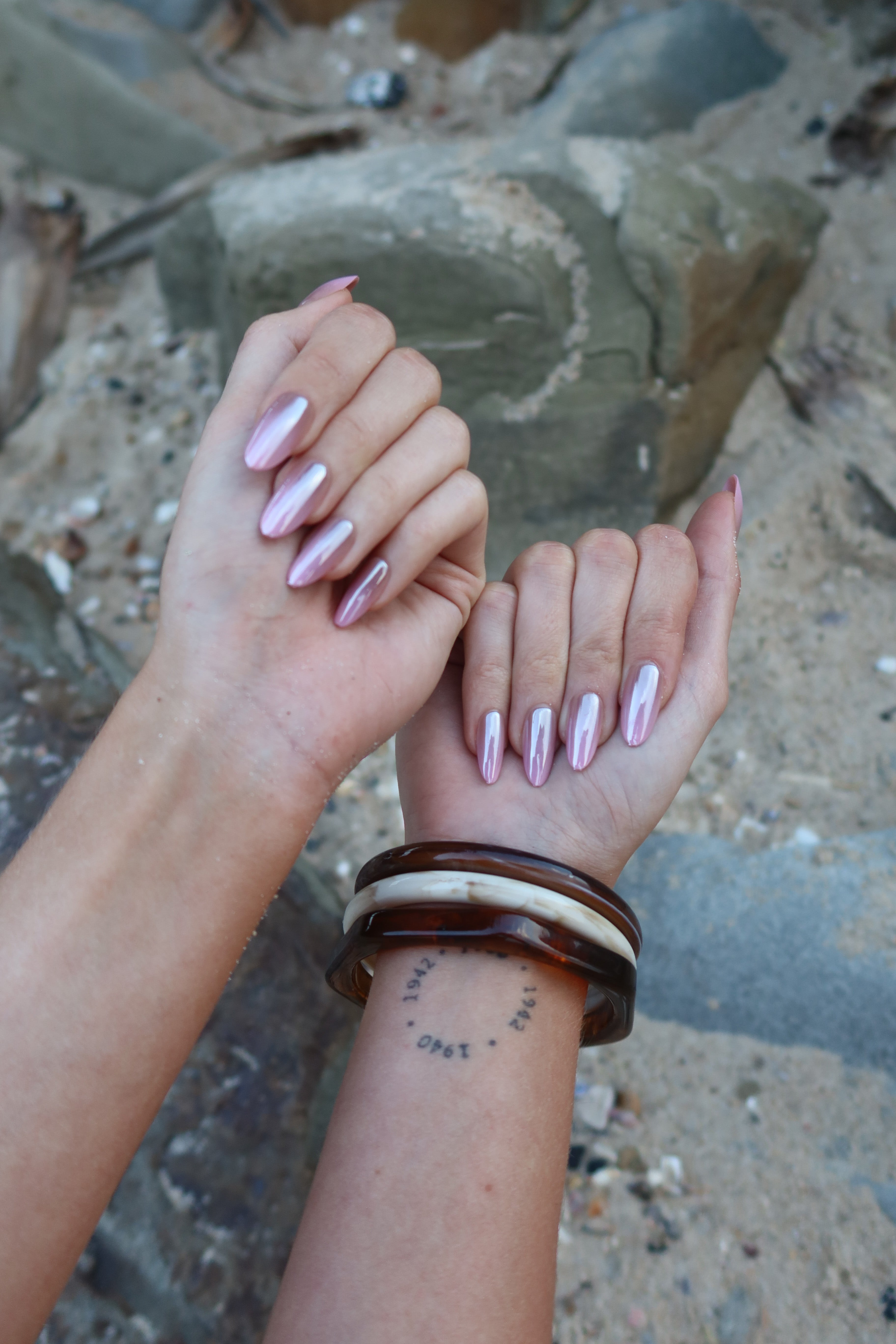 Two hands with Sugar Tips Sorbet Crush Pink Ombre Almond press-on nails held together against a natural background.