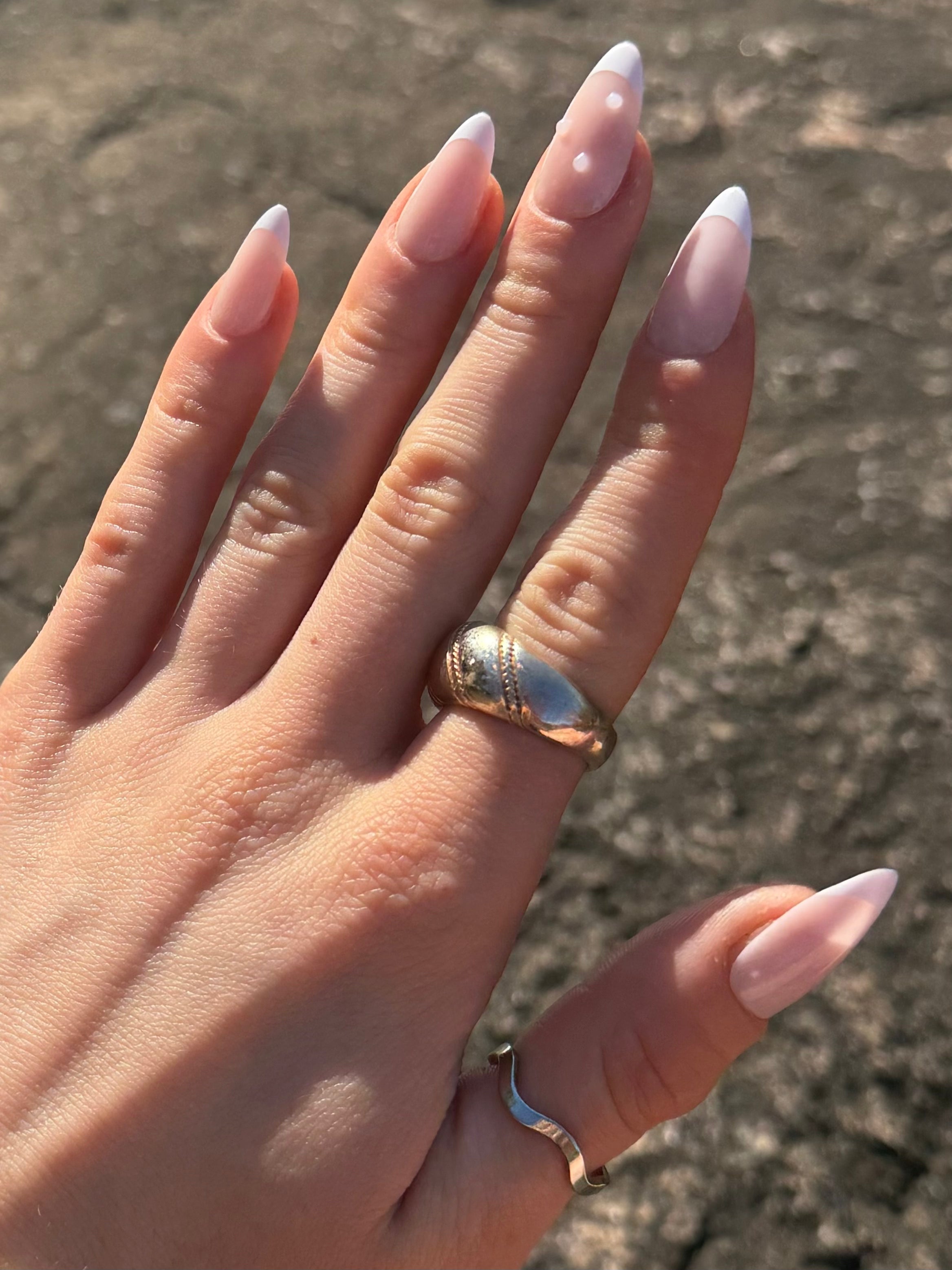 Hand showing French tip press on nails with pearls 