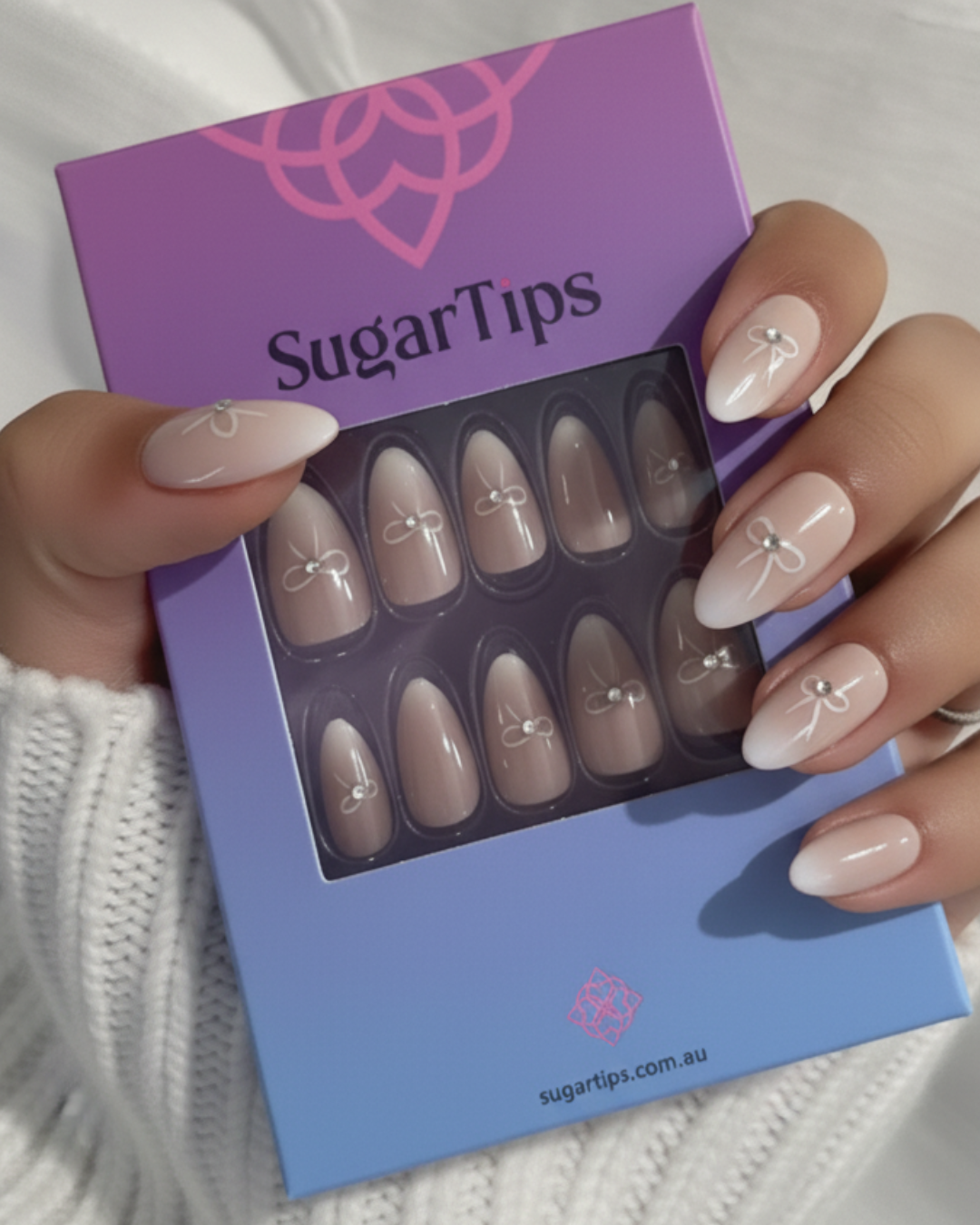 A hand wearing press on nails holding a box of press on nails