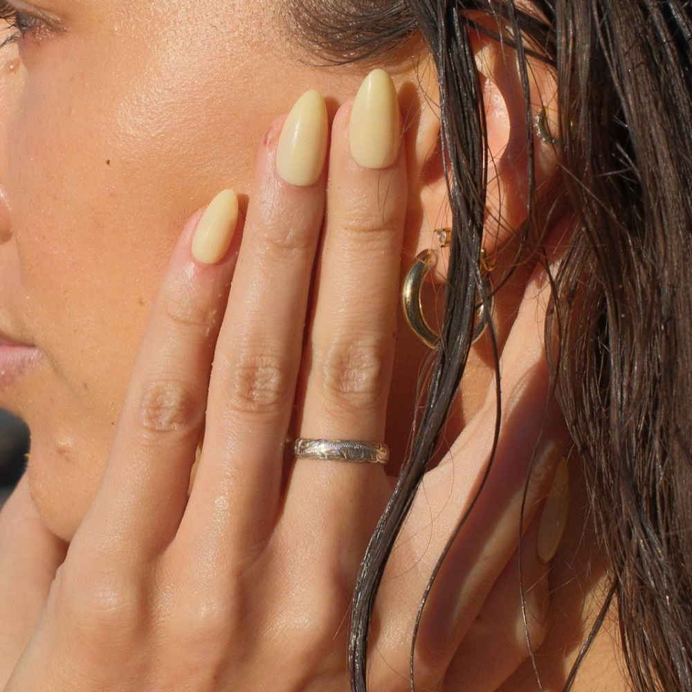 Butter Glow butter yellow press-on nails in medium almond by Sugar Tips, worn after a swim with wet hair and gold hoop
