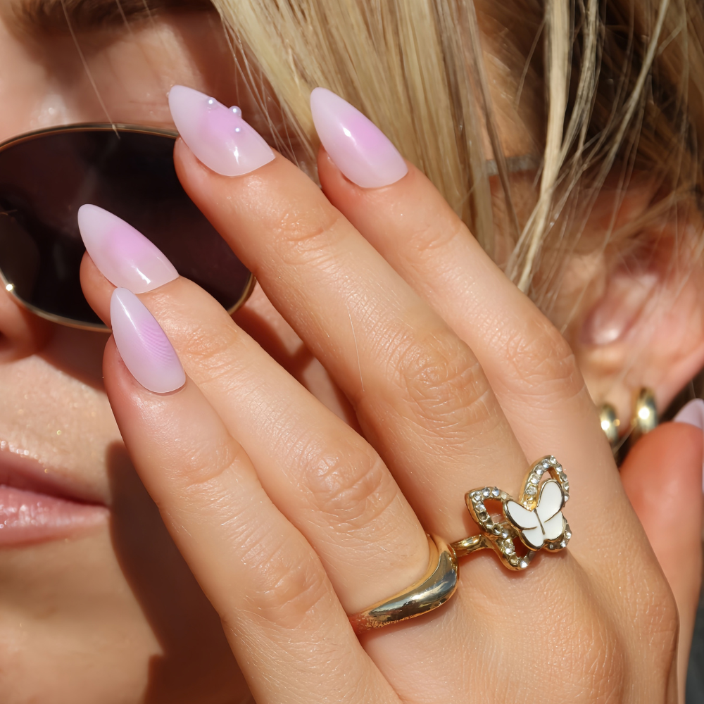 Close up shot of a hand over a face. Wearing high purple pink gloss press on nails from sugar tips 