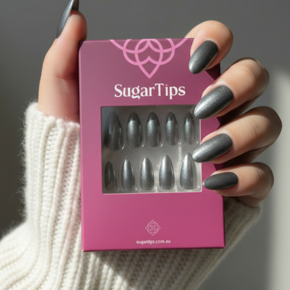 Hand holding a box of Sugar Tips press on nails wearing Metallic Silver Chrome Almond press on nails
